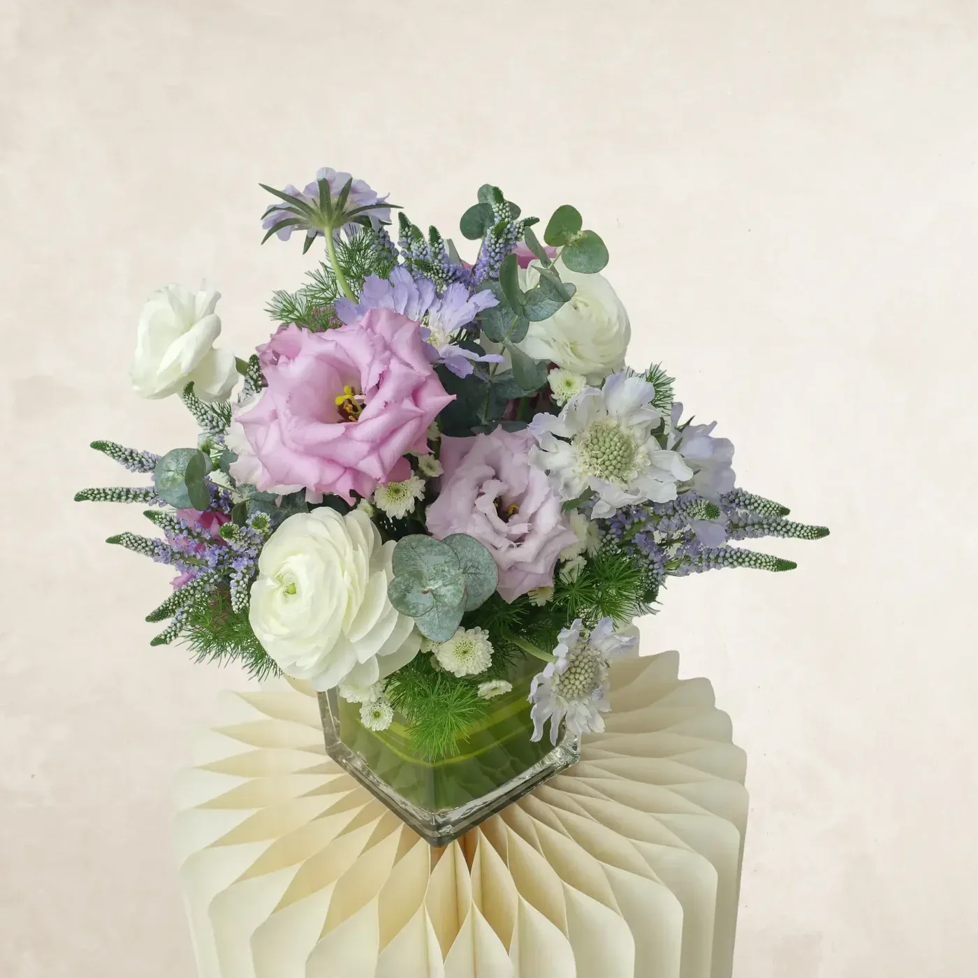 Beautiful pastel-colored floral bouquet with roses, lisianthus, and greenery in a glass vase.