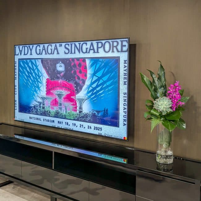 Elegant floral arrangement beside Lady Gaga Singapore concert poster.