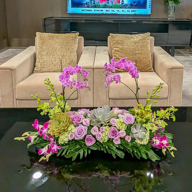 Elegant floral arrangement with pink orchids and roses at Jubilant Fields Floral Studio.