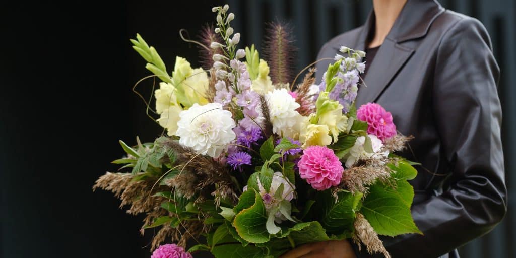 a florist holding a luxurious and lush flower bouquet