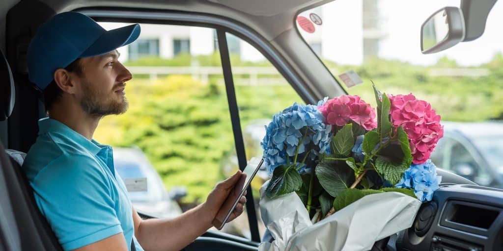 a flower delivery man in his vehicle with a bouquet of hydrangeas