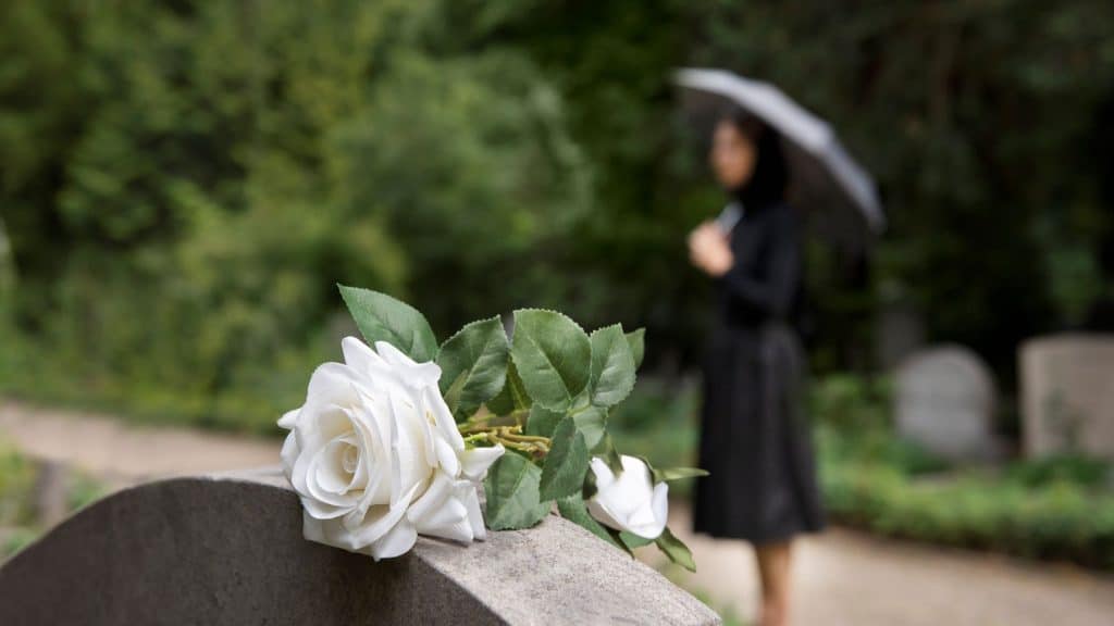 Elegant white funeral flower arrangement with roses and greenery.