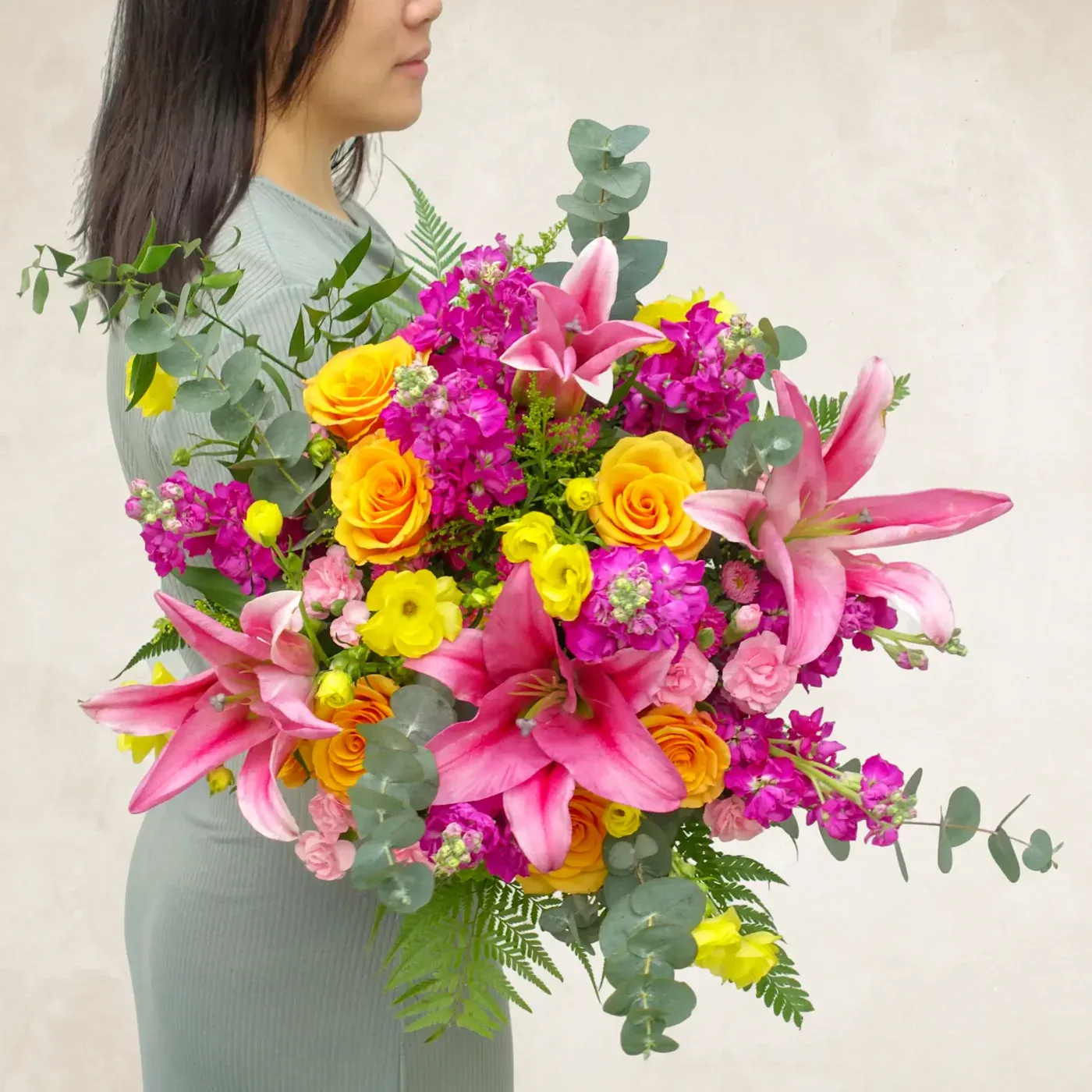 Vibrant floral arrangement with pink lilies, yellow roses, and purple blooms.