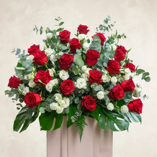 Elegant red and white roses with eucalyptus in a stylish display for restful occasions.