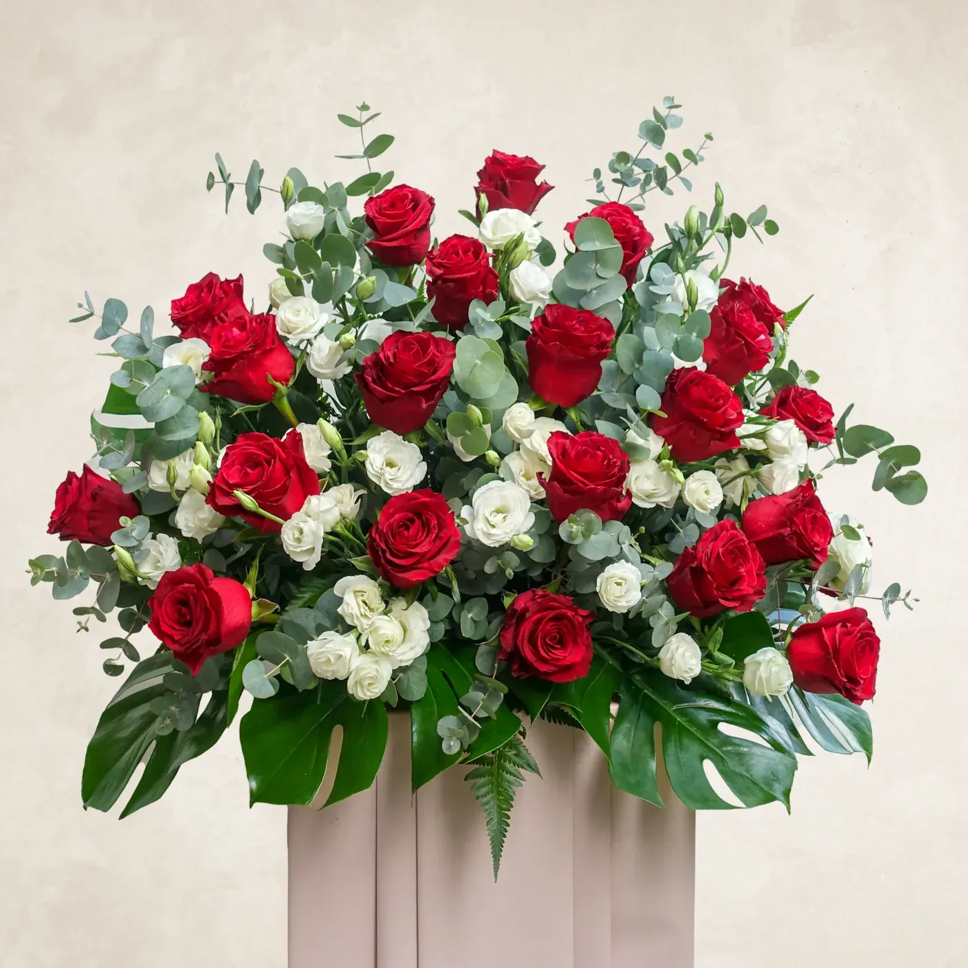 Elegant red and white roses with eucalyptus in a stylish display for restful occasions.