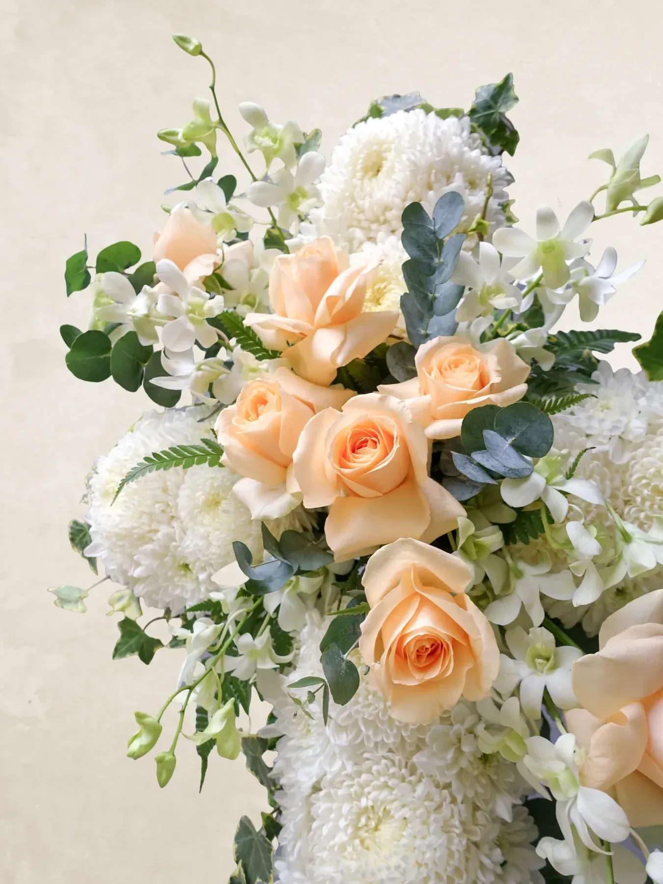 Beautiful floral bouquet featuring white and peach roses with lush greenery, perfect for a serene "R.