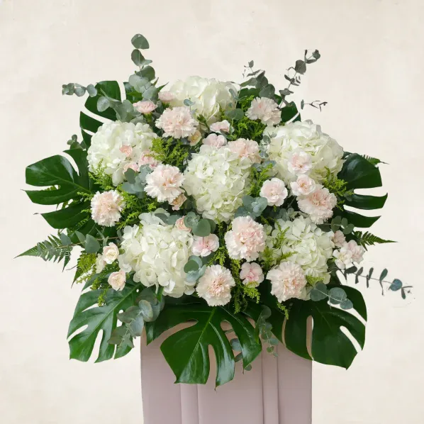 Elegant white and pink floral arrangement with lush greenery for a peaceful resting space.