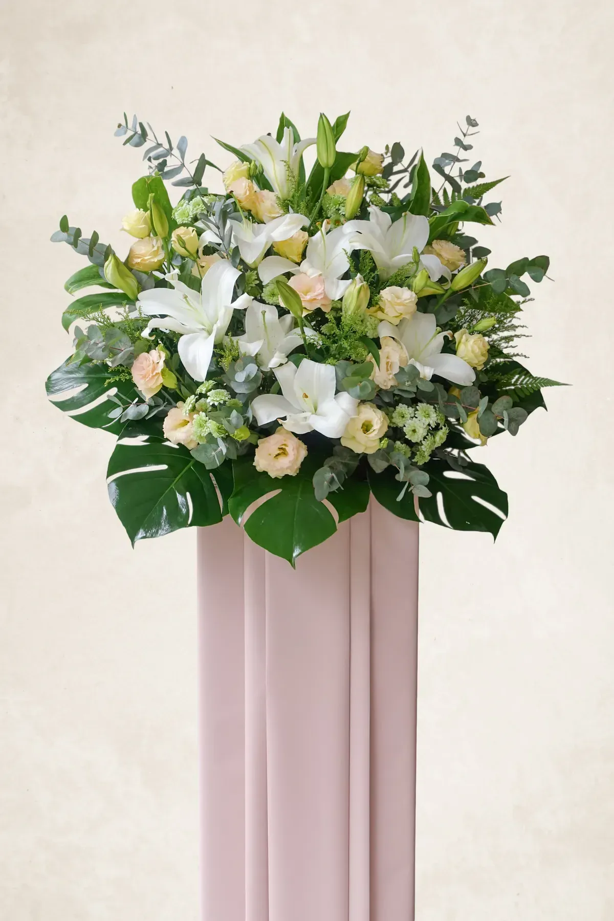 Beautiful white lilies and roses in a lush floral display for memorial or tribute occasions.