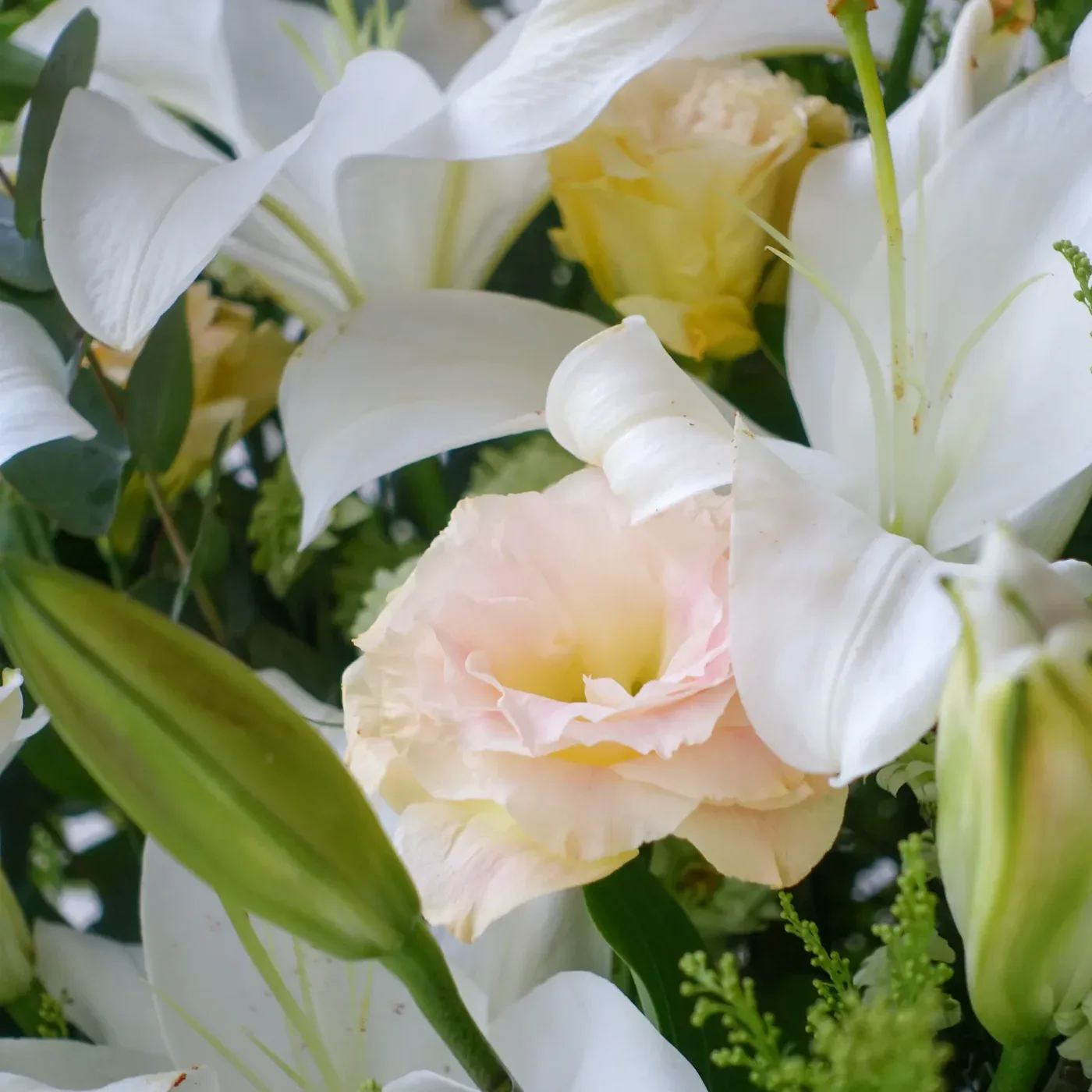 Elegant floral display with white lilies and soft pink roses.