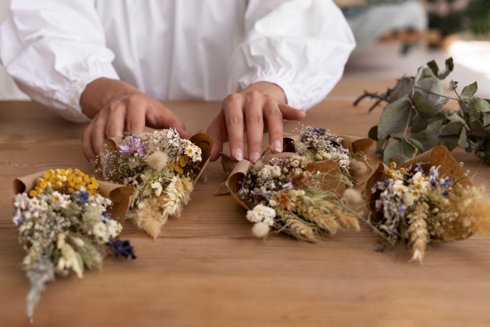 Person arranging dried flower bouquets with blue hydrangeas and other blooms.