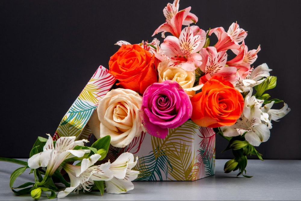 Beautiful mixed floral bouquet with roses and lilies in a decorative box.