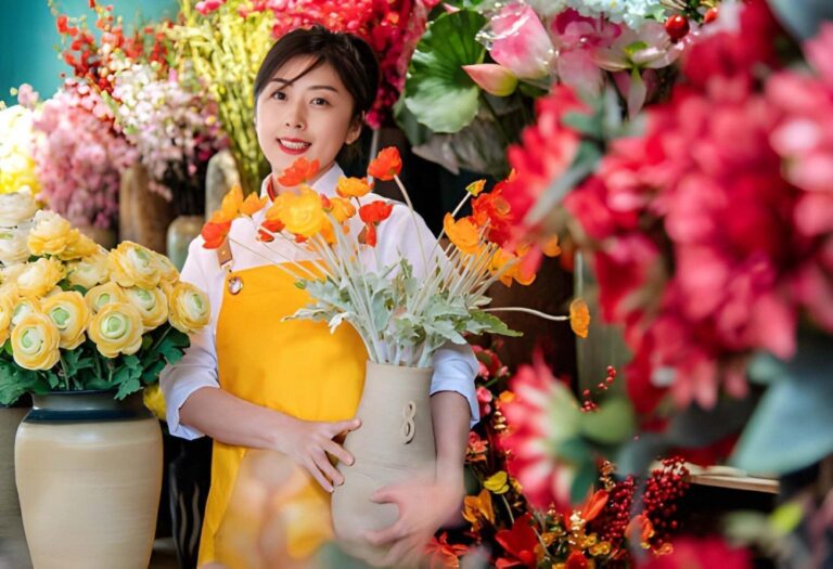 Woman holding a bouquet of colorful flowers in a floral studio setting.